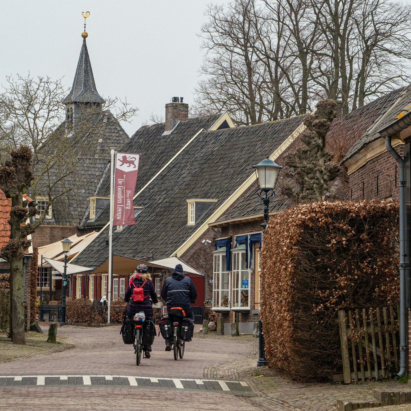 Twee fietsers rijden over een historische straat met klinkers.