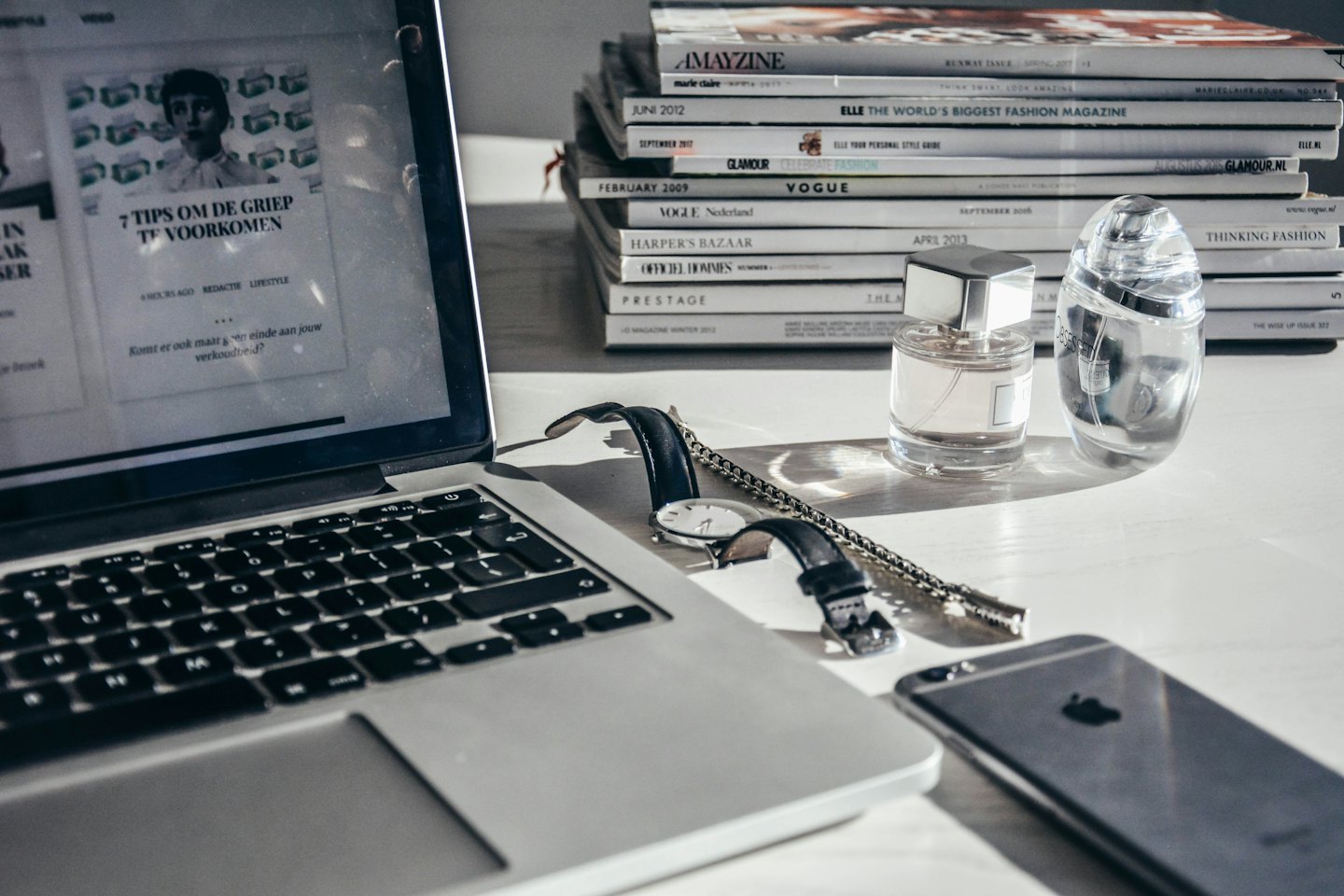 Moderne bureau met laptop, telefoon, horloge en parfumflesjes.